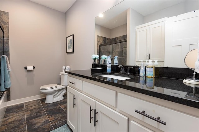 bathroom featuring vanity, a shower with shower door, and toilet