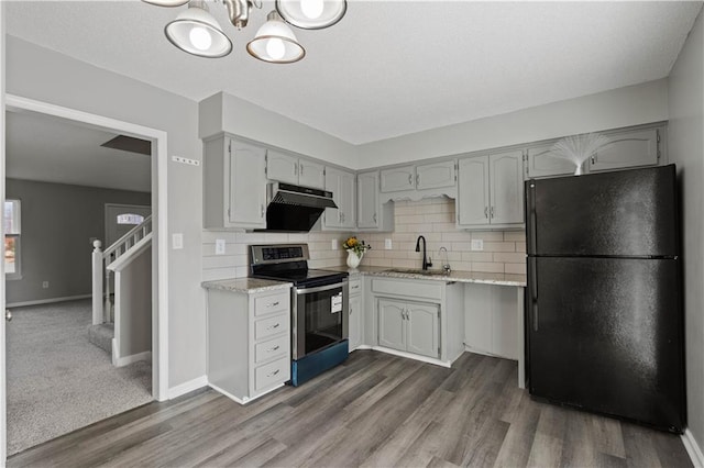 kitchen with dark hardwood / wood-style flooring, stainless steel electric stove, sink, and black fridge