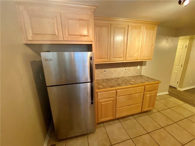 kitchen featuring stainless steel fridge, light brown cabinets, backsplash, and light tile patterned flooring