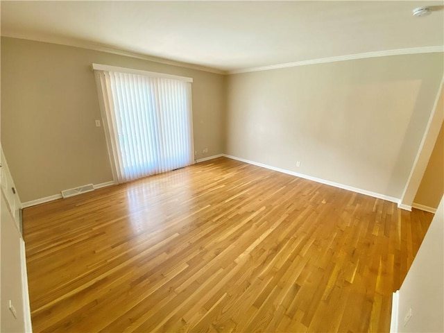 empty room featuring ornamental molding and light hardwood / wood-style flooring