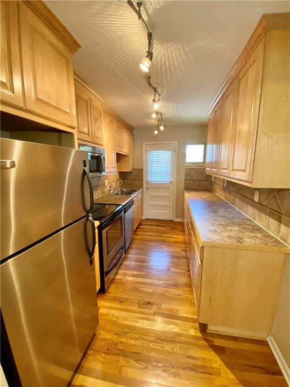 kitchen with light brown cabinetry, stainless steel appliances, and light wood-type flooring