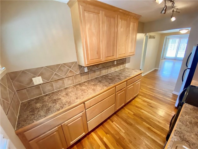 kitchen featuring backsplash, light brown cabinets, and light wood-type flooring