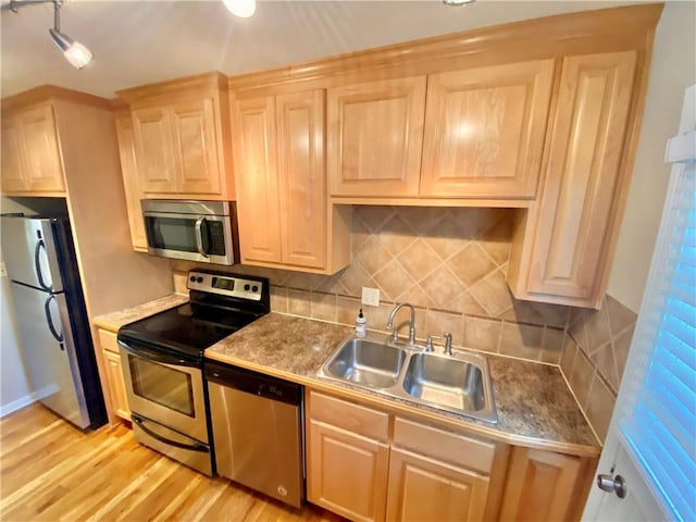 kitchen featuring appliances with stainless steel finishes, sink, light wood-type flooring, and light brown cabinets