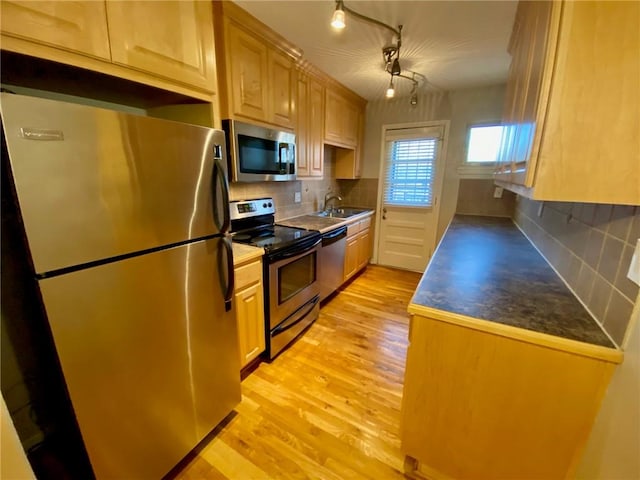 kitchen with sink, decorative backsplash, stainless steel appliances, and light hardwood / wood-style floors