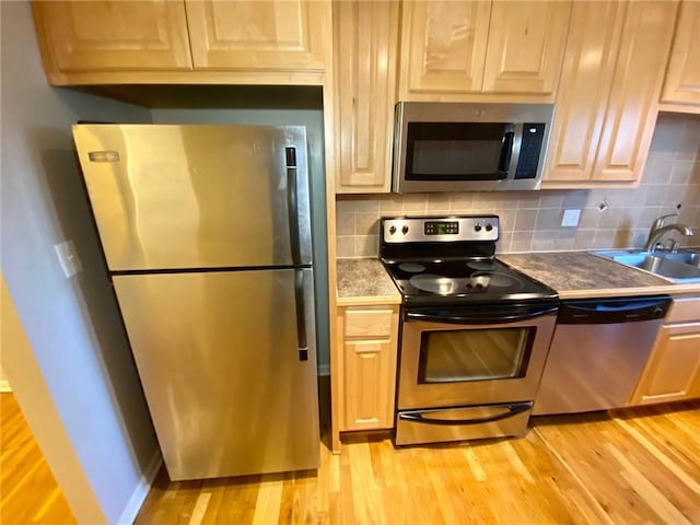 kitchen with light hardwood / wood-style floors, appliances with stainless steel finishes, sink, and backsplash