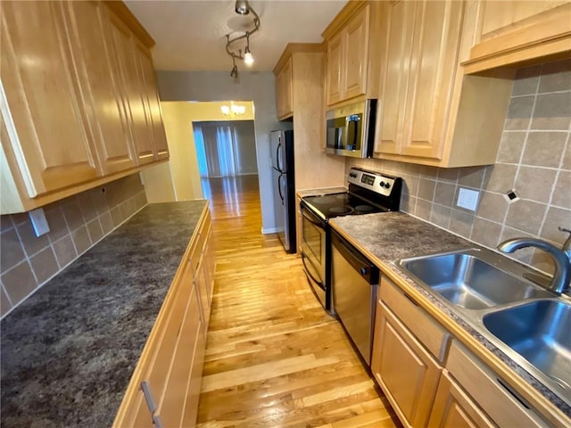 kitchen with decorative backsplash, light brown cabinets, sink, light wood-type flooring, and appliances with stainless steel finishes