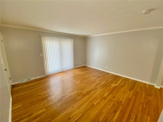 empty room featuring ornamental molding and hardwood / wood-style flooring