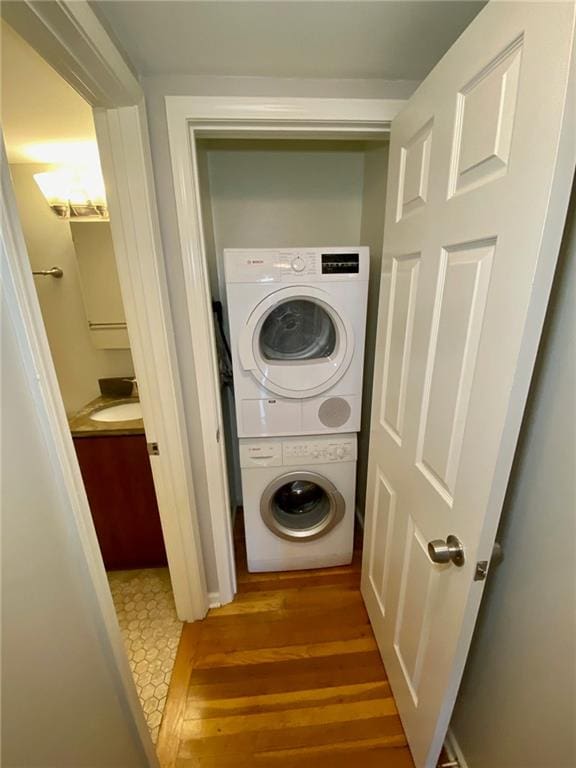 laundry area featuring stacked washer / dryer and wood-type flooring