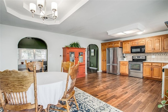 403 S Jackson St, Archie, MO 64725 - kitchen with appliances with stainless steel finishes, light countertops, a chandelier, arched walkways, and dark wood-type flooring