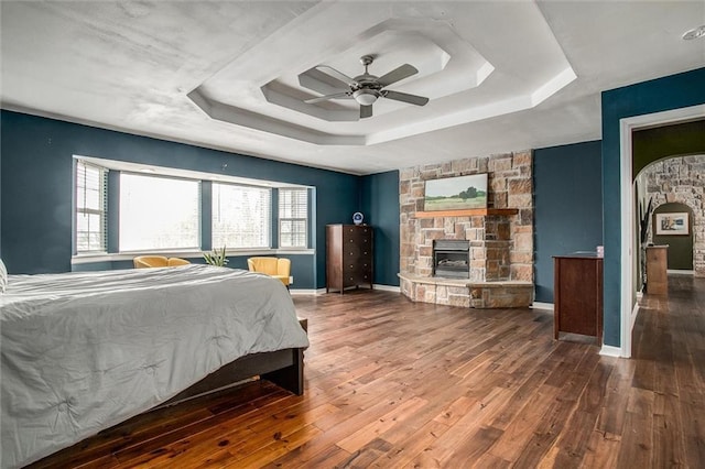 403 S Jackson St, Archie, MO 64725 - bedroom featuring a tray ceiling, hardwood / wood-style floors, multiple windows, and a stone fireplace