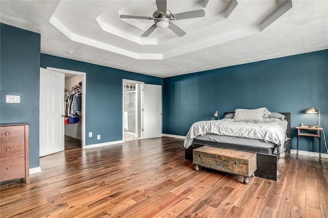 403 S Jackson St, Archie, MO 64725 - bedroom featuring a tray ceiling, wood finished floors, a walk in closet, and ceiling fan