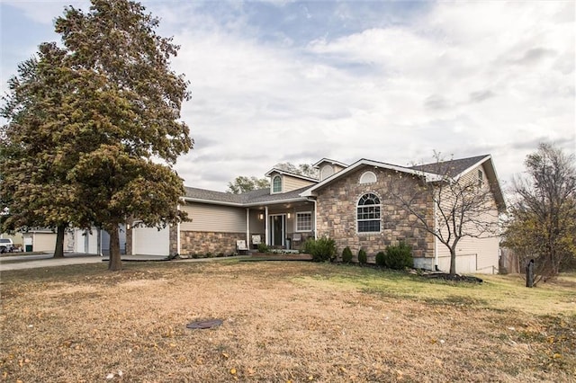 403 S Jackson St, Archie, MO 64725 - view of front of house featuring a garage, a front lawn, stone siding, and a porch