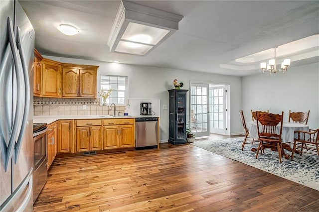 403 S Jackson St, Archie, MO 64725 - kitchen featuring appliances with stainless steel finishes, light wood-style floors, light countertops, a chandelier, and backsplash