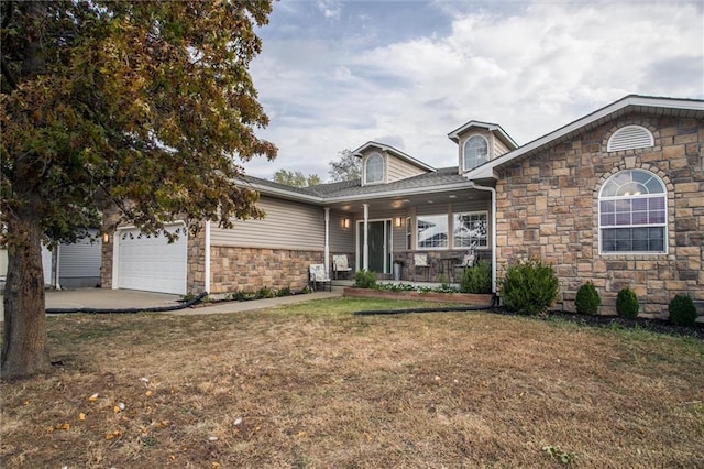403 S Jackson St, Archie, MO 64725 - view of front of house featuring stone siding, a front lawn, covered porch, a garage, and driveway