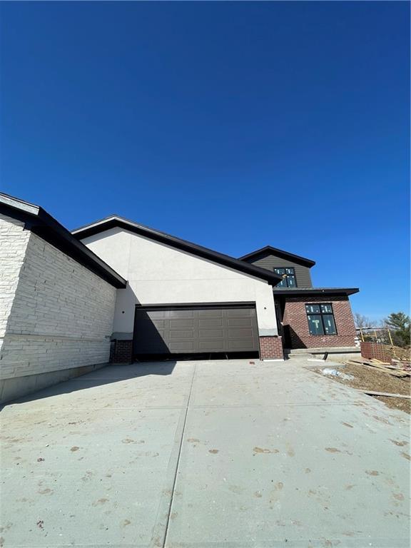 exterior space with brick siding, stucco siding, and concrete driveway