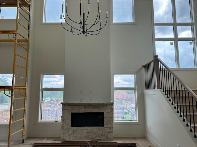 2846 W 133rd Ter, Leawood, KS 66209 - unfurnished living room with a high ceiling, stairway, a chandelier, a stone fireplace, and baseboards