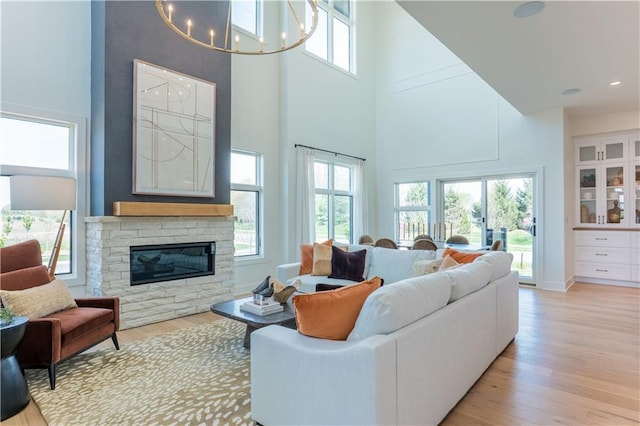 2846 W 133rd Ter, Leawood, KS 66209 - living area featuring a towering ceiling, light wood-style floors, a chandelier, and a stone fireplace