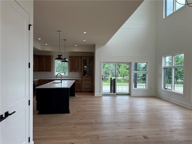 2846 W 133rd Ter, Leawood, KS 66209 - kitchen with an island with sink, light wood finished floors, a towering ceiling, light countertops, and open floor plan