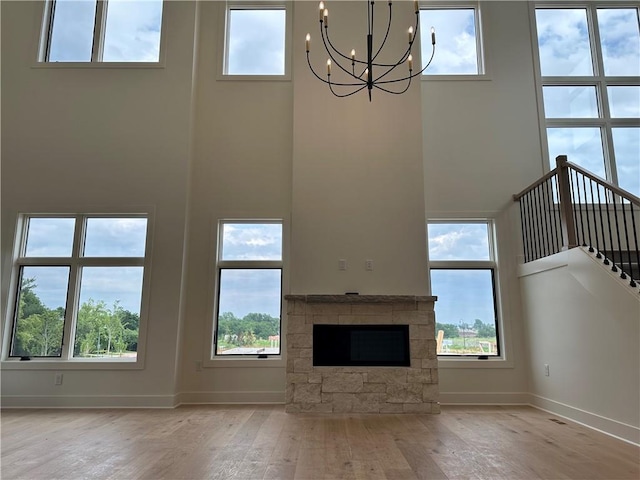 2846 W 133rd Ter, Leawood, KS 66209 - unfurnished living room featuring a high ceiling, hardwood / wood-style floors, a chandelier, a fireplace, and stairs