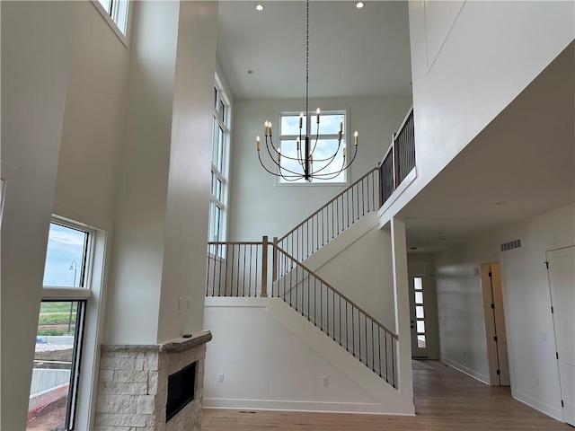 2846 W 133rd Ter, Leawood, KS 66209 - staircase featuring a high ceiling, a chandelier, wood finished floors, a stone fireplace, and recessed lighting