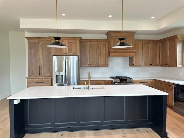 2846 W 133rd Ter, Leawood, KS 66209 - kitchen featuring appliances with stainless steel finishes, a center island with sink, decorative backsplash, light wood-style floors, and brown cabinetry