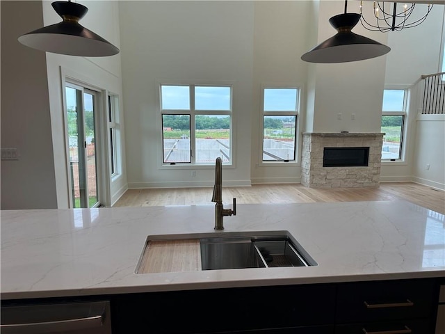 2846 W 133rd Ter, Leawood, KS 66209 - kitchen featuring open floor plan, a high ceiling, wood finished floors, light stone countertops, and decorative light fixtures