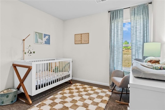 bedroom featuring dark colored carpet and a nursery area