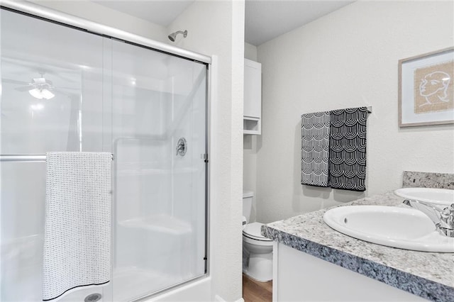 bathroom with vanity, toilet, walk in shower, and ceiling fan