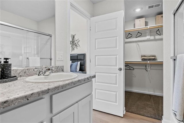 bathroom with wood-type flooring, vanity, and an enclosed shower