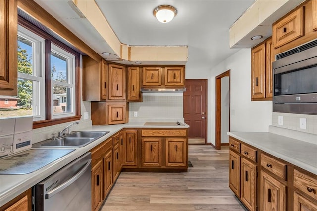 kitchen with light hardwood / wood-style flooring, decorative backsplash, stainless steel appliances, and sink