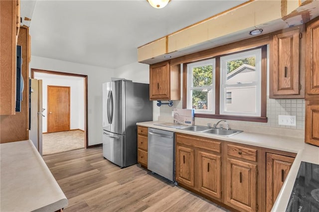 kitchen with sink, appliances with stainless steel finishes, light hardwood / wood-style flooring, and tasteful backsplash