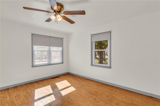 empty room with a wealth of natural light, light hardwood / wood-style floors, and ceiling fan