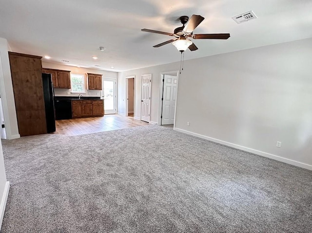 unfurnished living room featuring light carpet and ceiling fan