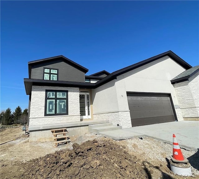 view of front of house featuring stone siding, stucco siding, an attached garage, and concrete driveway