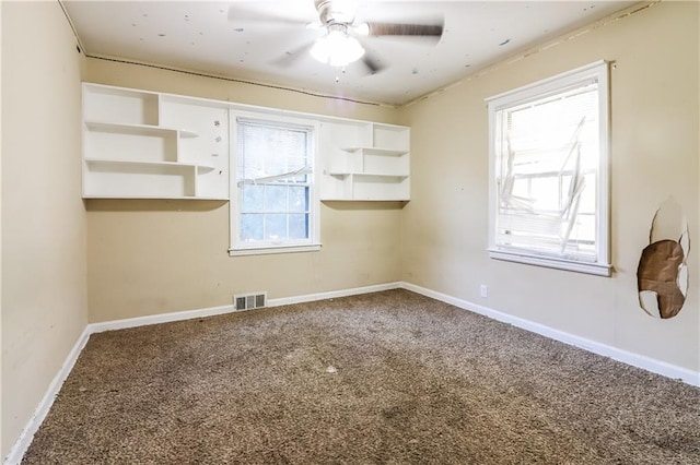 carpeted spare room featuring a wealth of natural light and ceiling fan