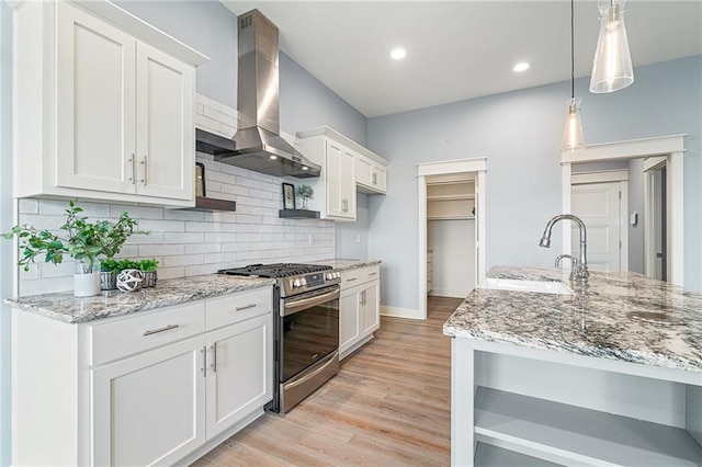 kitchen featuring pendant lighting, white cabinets, stainless steel gas range, exhaust hood, and sink