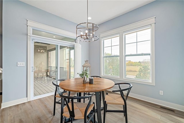 dining space featuring light hardwood / wood-style flooring and a notable chandelier