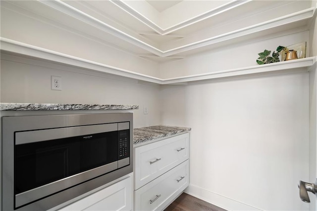 kitchen with stainless steel microwave, dark wood-type flooring, white cabinetry, and light stone countertops