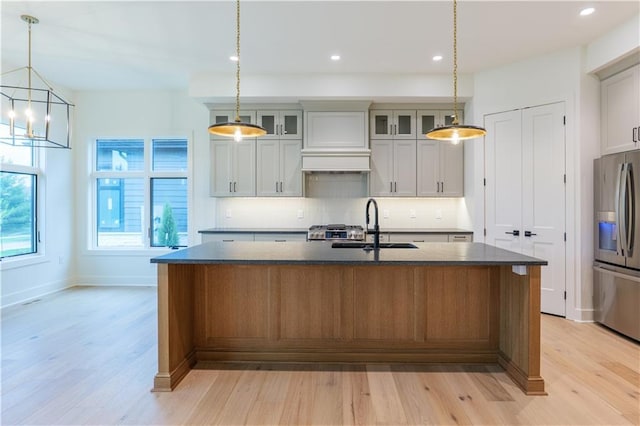 2852 W 133rd Ter, Leawood, KS 66209 - kitchen with stainless steel fridge, light wood-type flooring, backsplash, a kitchen island with sink, and a sink