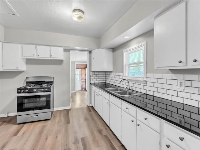 kitchen with decorative backsplash, sink, white cabinets, gas stove, and light hardwood / wood-style floors