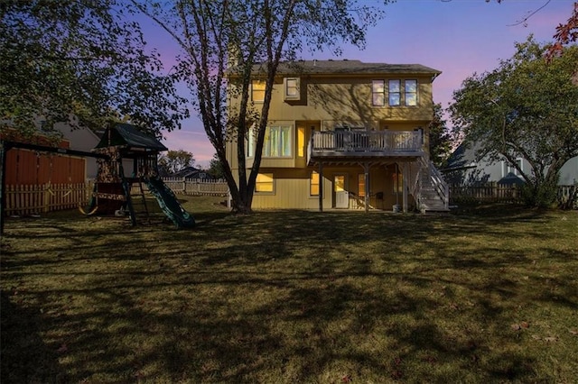 back house at dusk with a playground and a lawn