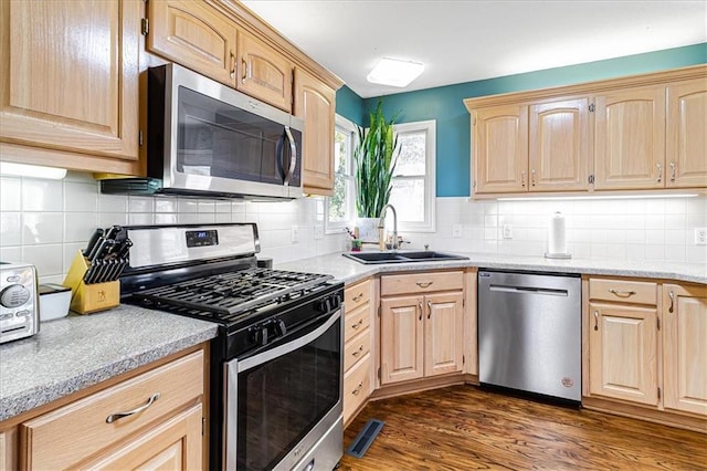 kitchen featuring decorative backsplash, appliances with stainless steel finishes, light brown cabinetry, dark wood-type flooring, and sink