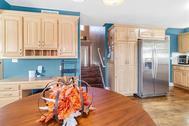 kitchen with light brown cabinetry, stainless steel fridge with ice dispenser, and hardwood / wood-style floors