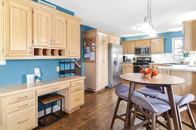 kitchen featuring pendant lighting, dark hardwood / wood-style floors, light brown cabinetry, and appliances with stainless steel finishes