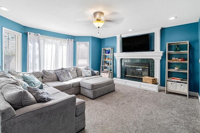 living room with carpet flooring, ceiling fan, and a tile fireplace