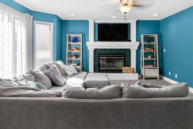 carpeted living room featuring ceiling fan and a tiled fireplace