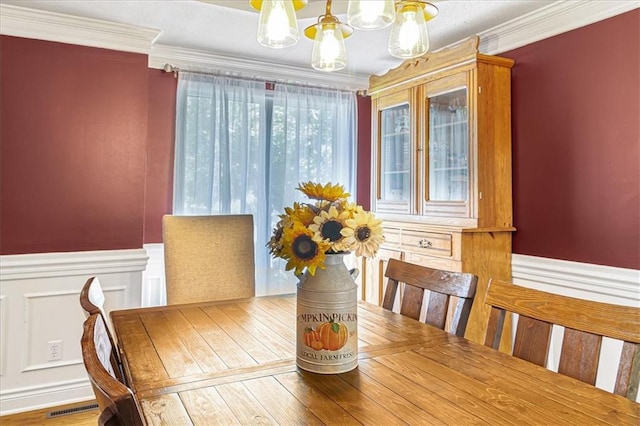 dining space with hardwood / wood-style floors, ornamental molding, and a chandelier