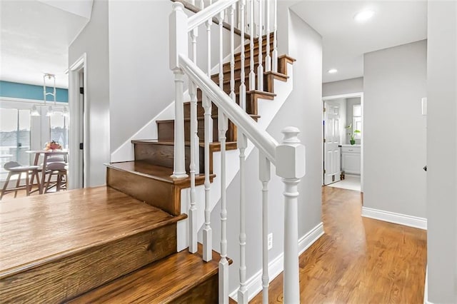 staircase featuring an inviting chandelier and hardwood / wood-style flooring