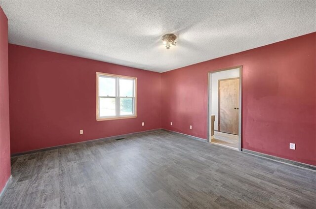 unfurnished room featuring dark hardwood / wood-style floors and a textured ceiling