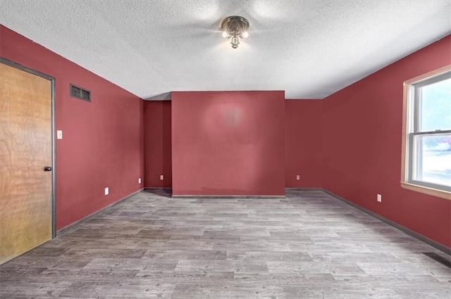 unfurnished room featuring light hardwood / wood-style floors and a textured ceiling